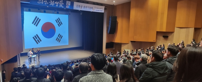 김홍성의 화성愛 출판기념회 참가자들이 국기에 대한 경례를 하고 있다.