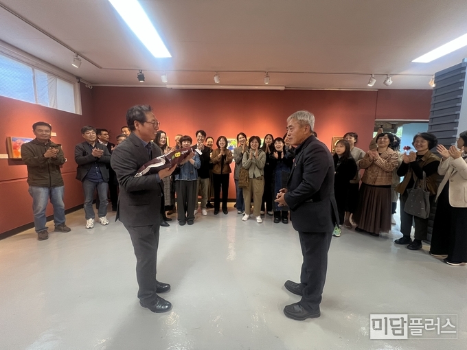 예물교환전을 기획한 박석윤 창문아트센터장이 마을이장께 수향미를 받고 있다. 박수치는 작가와 내외빈